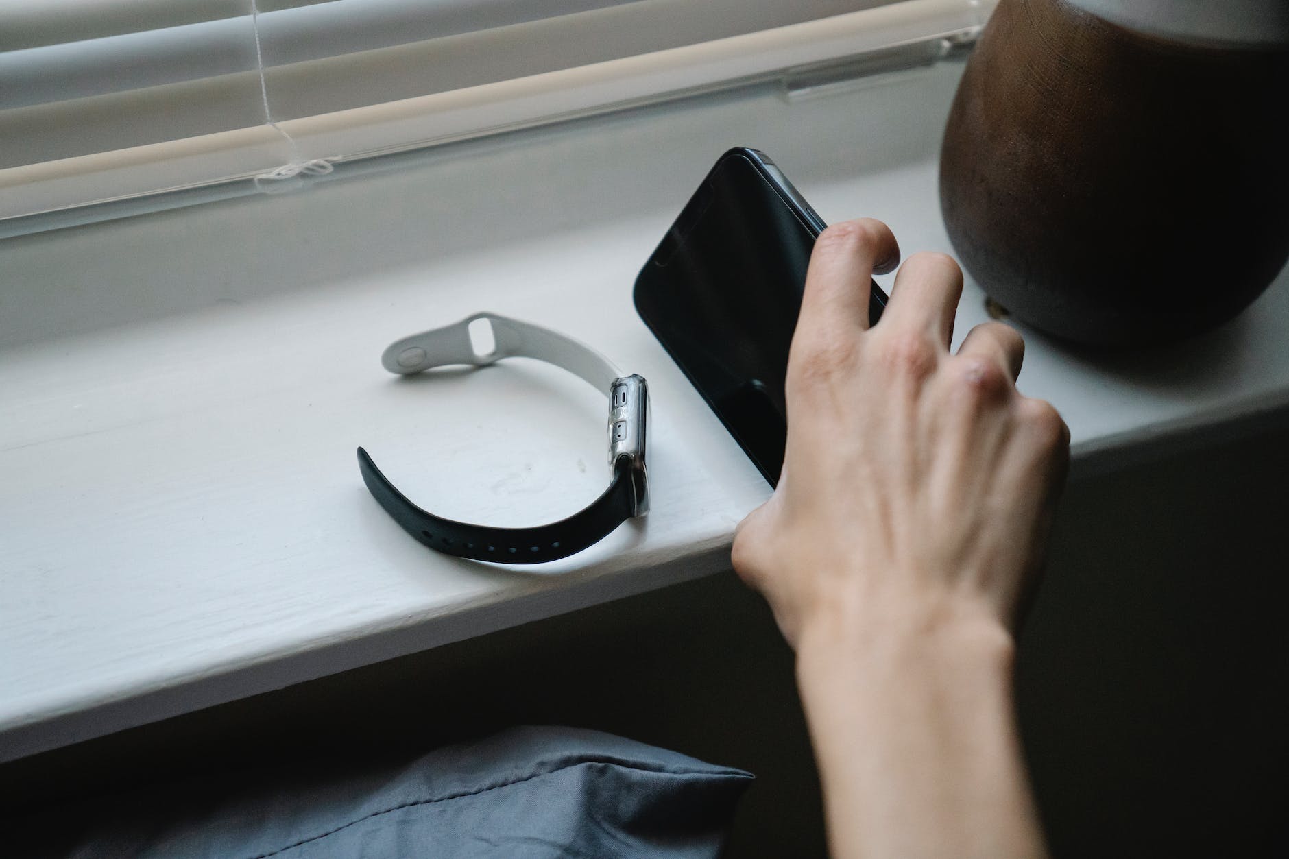 person with smartphone and wristwatch in bedroom